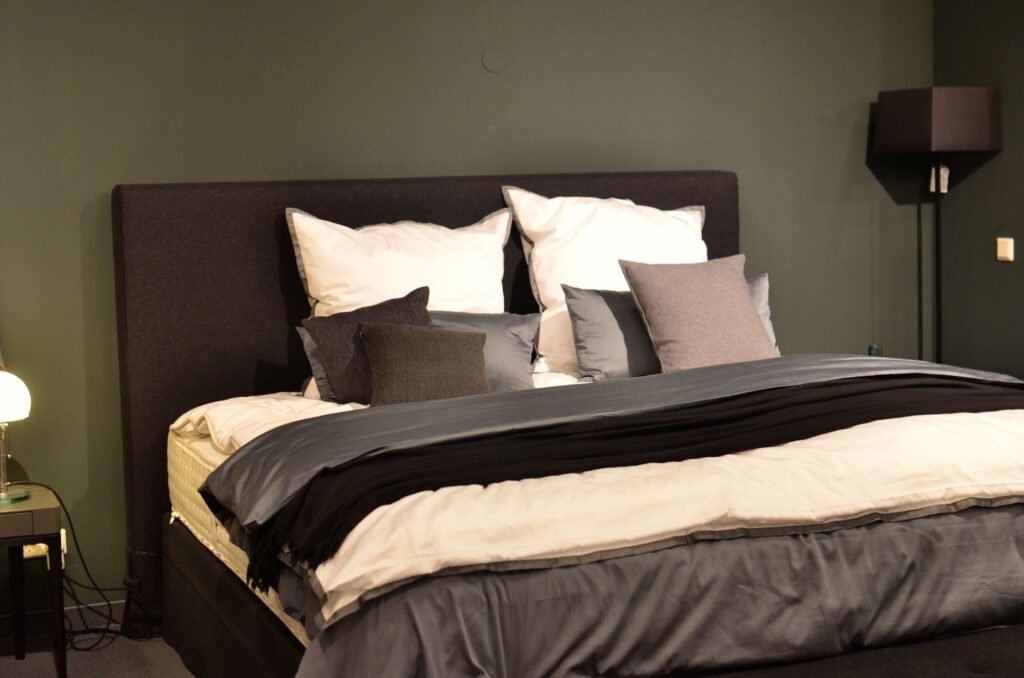 Creative design of bed with collection of cushions and cover between lamps in house
